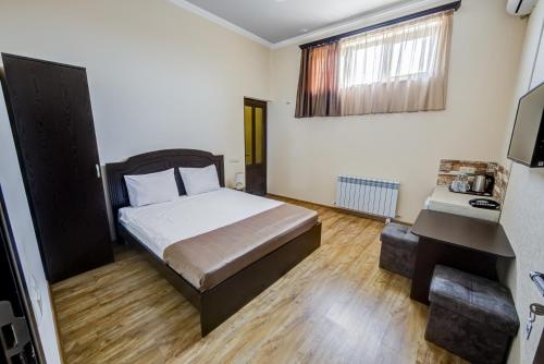 a bedroom with a bed and a desk and a television at H Resort Hotel Vagharshapat Armenia in Vagharshapat