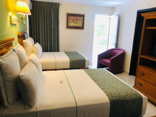 a hotel room with two beds and a chair at Hotel Francis in Culiacán