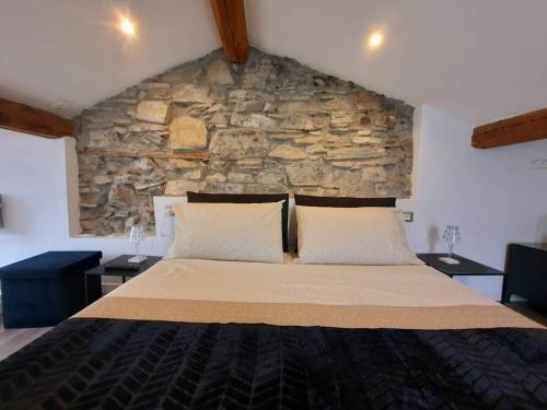 a large bed in a room with a stone wall at Luxury Room La Terrazza sul Lago di Como in Blevio