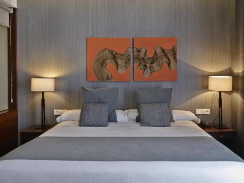 a bedroom with a large bed with three paintings on the wall at Hotel Carris Marineda in A Coruña