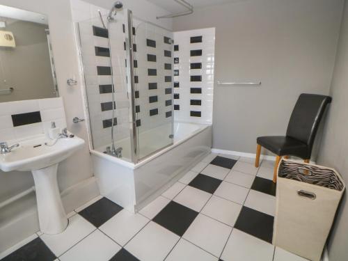 La salle de bains est pourvue d'une douche, d'un lavabo et d'une chaise. dans l'établissement East Bank Cottage, à Matlock