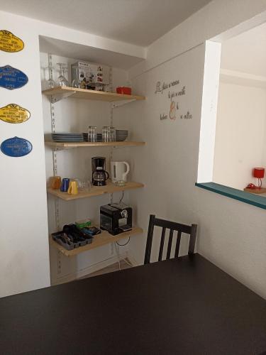 a kitchen with a table and a microwave on a shelf at Studio Bourbon in Bourbon-lʼArchambault