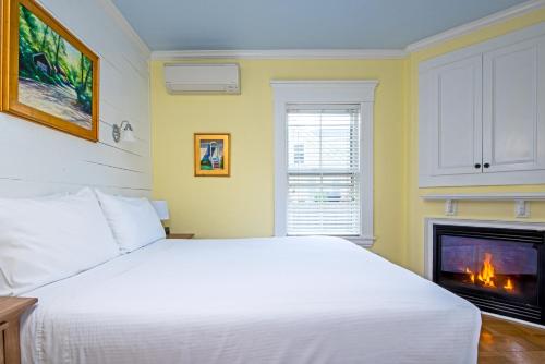 a bedroom with a white bed and a fireplace at Admiral's Landing in Provincetown