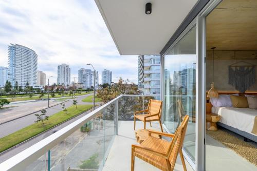 a bedroom with a balcony with a bed and a view of a city at Ambar Hotel in Punta del Este