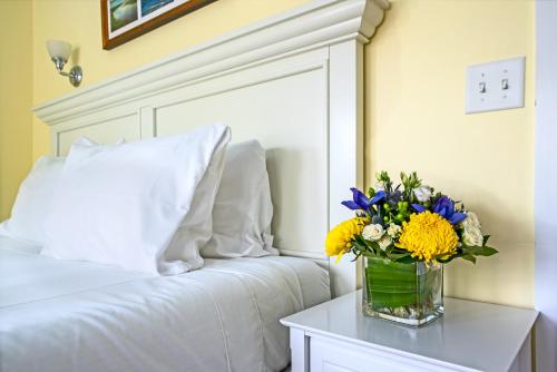 a vase of flowers on a table next to a bed at Admiral's Landing in Provincetown