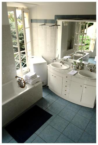 une salle de bain avec deux lavabos, une baignoire et un miroir dans l'établissement Appartement Claire Deluxe, à Cannes