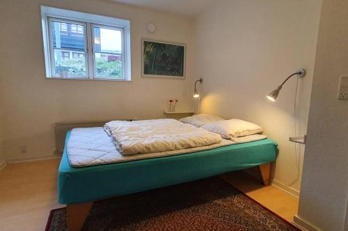 Cama con marco verde en habitación con ventana en Nice and cozy flat en Nuuk