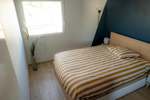 1 dormitorio con cama de rayas y ventana en Le Saint Jame, proche Parc Rivière, en Burdeos