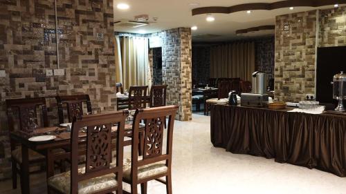 un restaurante con mesa, sillas y paredes de ladrillo en Muscat Horizon Hotel, en Mawāliḩ