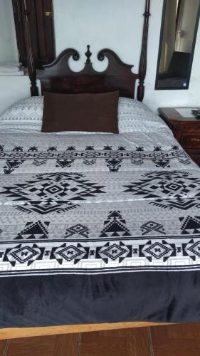 a bed with a black and white quilt on it at Cabaña Aurora in Zirahuén