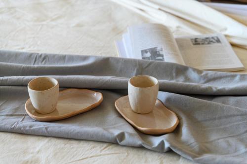 two coffee cups and two plates on a bed at Ambar Hotel in Punta del Este