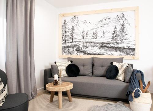 a living room with a couch and a drawing of a mountain at Apartamenty Grapa Resort 2xSauny 2xSale zabaw Balia Kulkolandia in Białka Tatrzańska