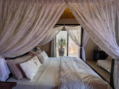 a bedroom with a canopy bed with curtains at Chameleon Backpackers & Guesthouse in Windhoek