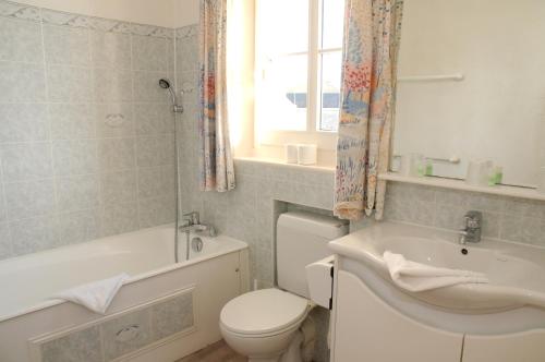 a bathroom with a toilet and a tub and a sink at La Taverne des Deux Augustins in Étretat