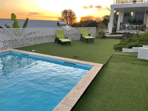 a backyard with a swimming pool and two chairs at Villa Blue Lodge in Saint-Louis