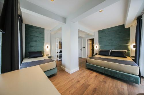 two beds in a large room with wooden floors at AXU AIRPORT HOTEL in Arnavutköy