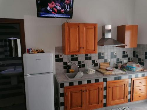 a kitchen with wooden cabinets and a white refrigerator at Casa Sofia Favignana in Favignana