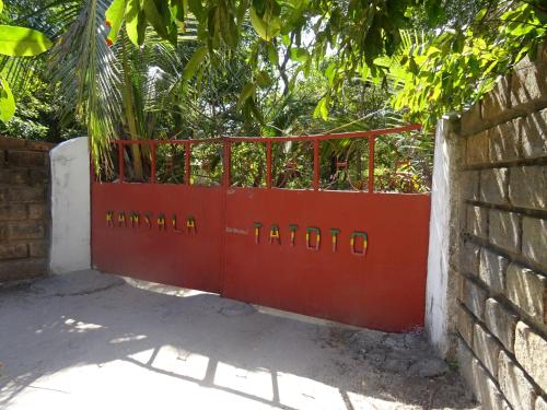 a red gate in front of a brick wall at Kansala Ta Toto in Kafountine