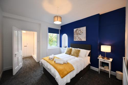 a blue bedroom with a large bed with a yellow blanket at The Wee Lion in Troon