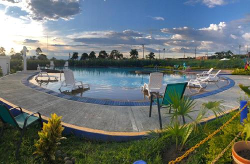 - une piscine avec des chaises et une piscine offrant une vue sur les orangers dans l'établissement Apartahotel en el eje cafetero cerca al Parque del Café, à Montenegro