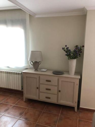 a room with a table with a lamp and flowers on it at Casa Picual, Mancha Real, Jaén in Mancha Real