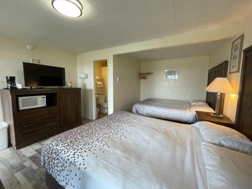 Habitación de hotel con 2 camas y TV de pantalla plana. en Holiday Motel en Westport