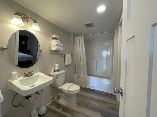 a bathroom with a sink and a toilet and a mirror at Holiday Motel in Westport