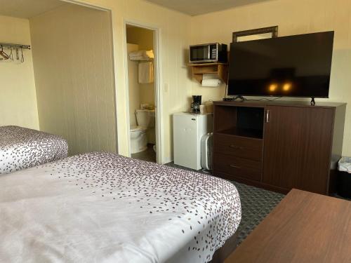a hotel room with a bed and a flat screen tv at Holiday Motel in Westport