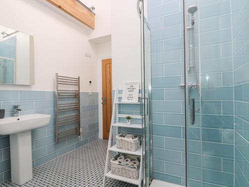 a bathroom with blue tiles and a shower at Wheal Grey in Germoe