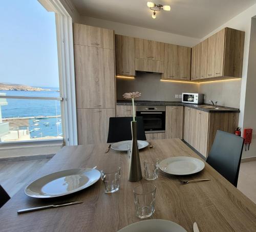 a kitchen with a table with plates and a vase with a flower at Lovely Apartment with Side Sea View in St Paul's Bay