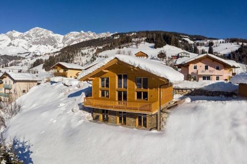 a house is covered in snow in a mountain at Chalet Ausblicklodge in Mühlbach am Hochkönig