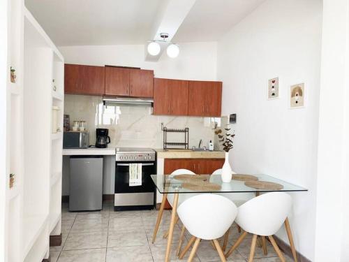 een keuken met een glazen tafel en 2 witte stoelen bij Detailed and Modern Apartment D in Guatemala