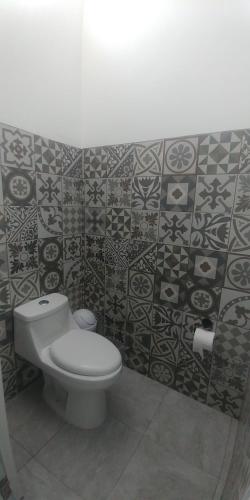 a bathroom with a toilet and tiles on the wall at Hotel Lucero Chan in Santa María del Oro