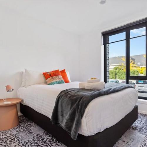 a bedroom with a large bed and a large window at Roomie Apartment Hotel in Auckland