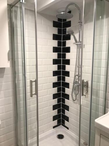 La salle de bains est pourvue d'une douche et d'un mur noir et blanc. dans l'établissement Villa patio classée proche océan, à Capbreton