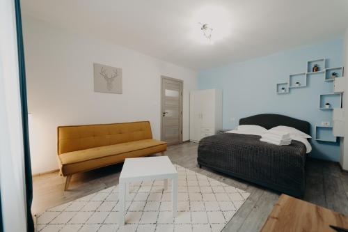 a bedroom with a bed and a couch and a table at Apartamentul Galben in Vatra Dornei