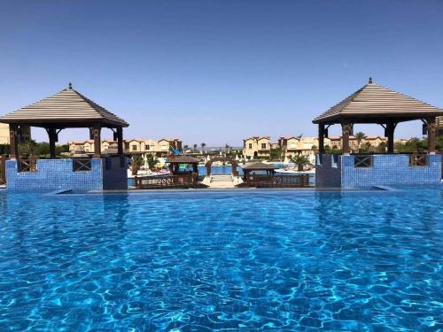 a swimming pool with two gazebos and blue water at Villa at Piacera Resort-seaview in Ain Sokhna