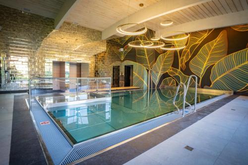 a swimming pool in a building with a mural on the wall at Santa Natura Resort & SPA in Nowa Wieś