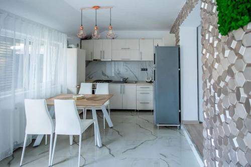 cocina con mesa de madera y sillas blancas en Casa Habitat, en Timisoara