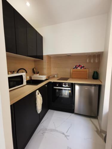 une cuisine avec des armoires noires et un four micro-ondes dans l'établissement Proche mer, vieille ville. Luxueux appartement, à Villefranche-sur-Mer
