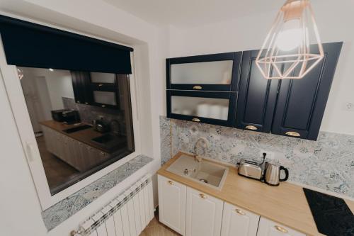 a kitchen with black cabinets and a sink and a mirror at Apartamentul Albastru in Vatra Dornei