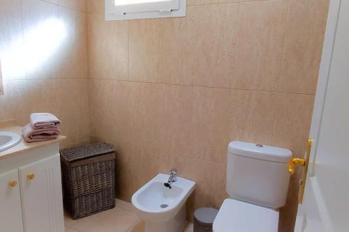 La salle de bains est pourvue de toilettes blanches et d'un lavabo. dans l'établissement Beach and pool view , 4 people, and free wifi, à Poris de Abona