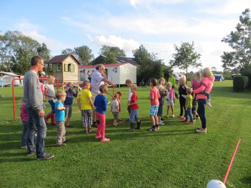 a group of children standing in a field playing baseball at Boerderijcamping Plantlust in Veere