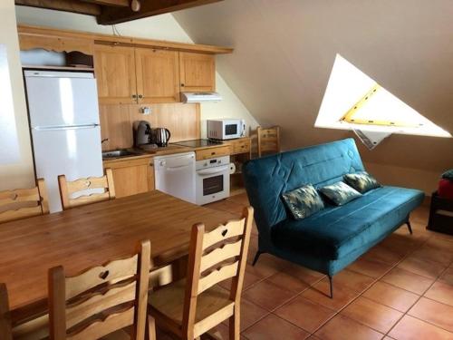 une cuisine avec une table à manger et un canapé bleu dans l'établissement Joli appartement avec terrasse vue sur les montagnes, à Uvernet