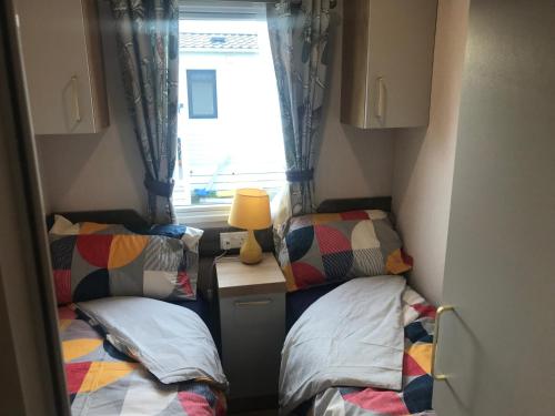 a small room with two beds and a window at Flamingo Land Private Caravan - No 8 Cedarwood in Kirby Misperton