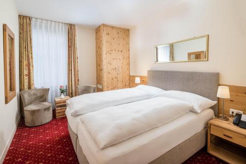 a hotel room with a large bed and a mirror at Boutique Hotel Engadinerhof - A Home for Generations in Pontresina