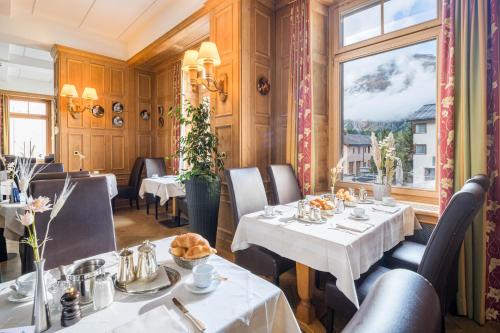 un restaurant avec des tables et des chaises et une fenêtre dans l'établissement Hotel Engadinerhof Superior, à Pontresina