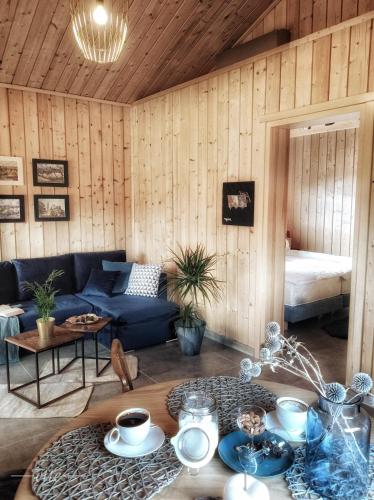 ein Wohnzimmer mit einem blauen Sofa und einem Tisch in der Unterkunft Kwitnące Jabłonie. Całoroczne Domki Wypoczynkowe in Obrazów