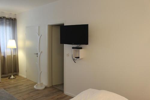 TV de pantalla plana en la pared de un dormitorio en Looks Inn, en Heidelberg