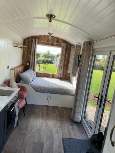 a bedroom with a bed and a window in a caravan at The Shepherd’s Nest in Bristol